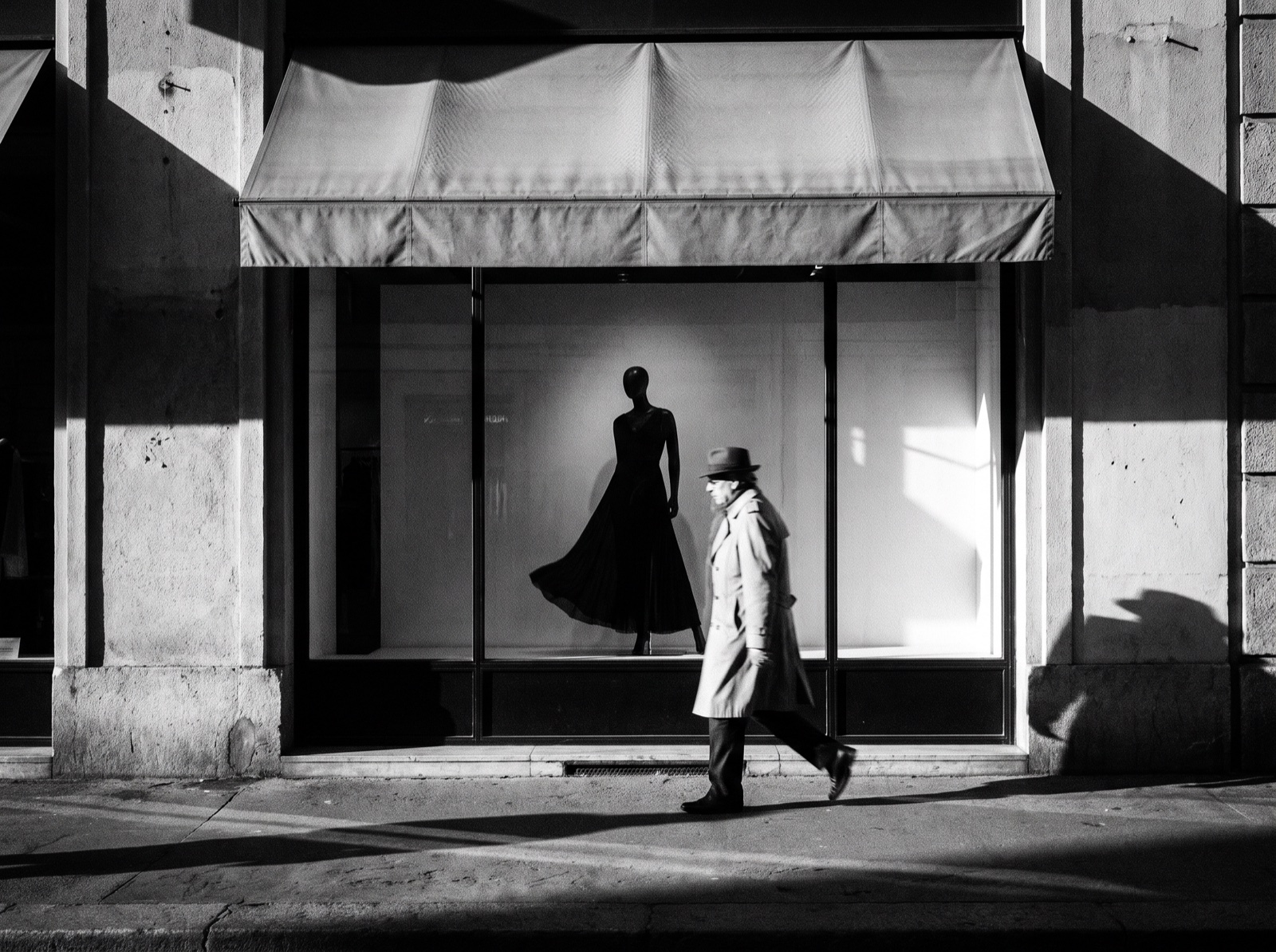 Black-and-white photograph of a boutique storefront with a passer-by in motion blur